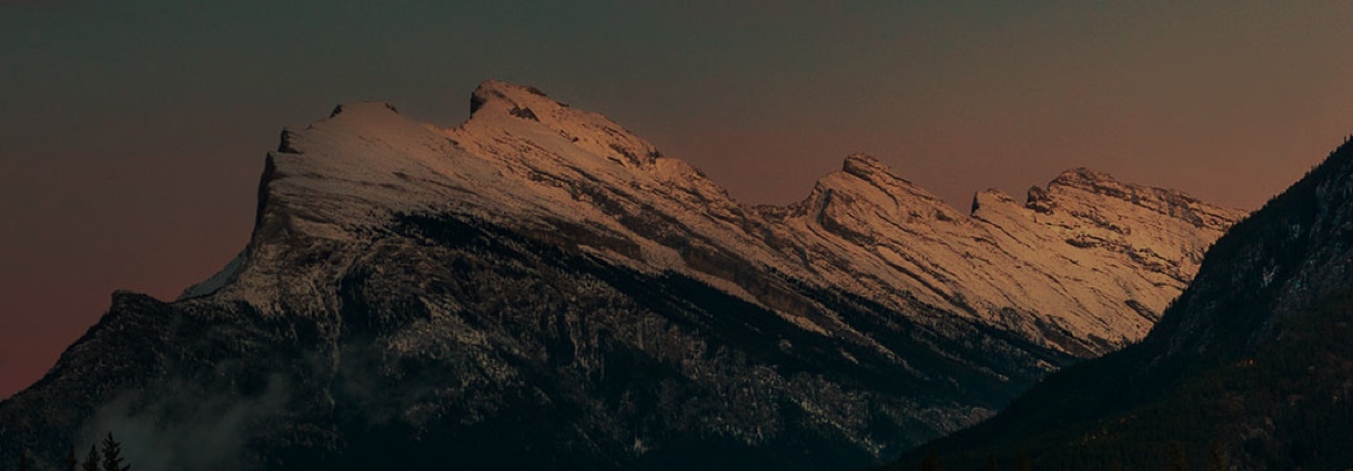 Snowcapped mountain under clear sky at dusk